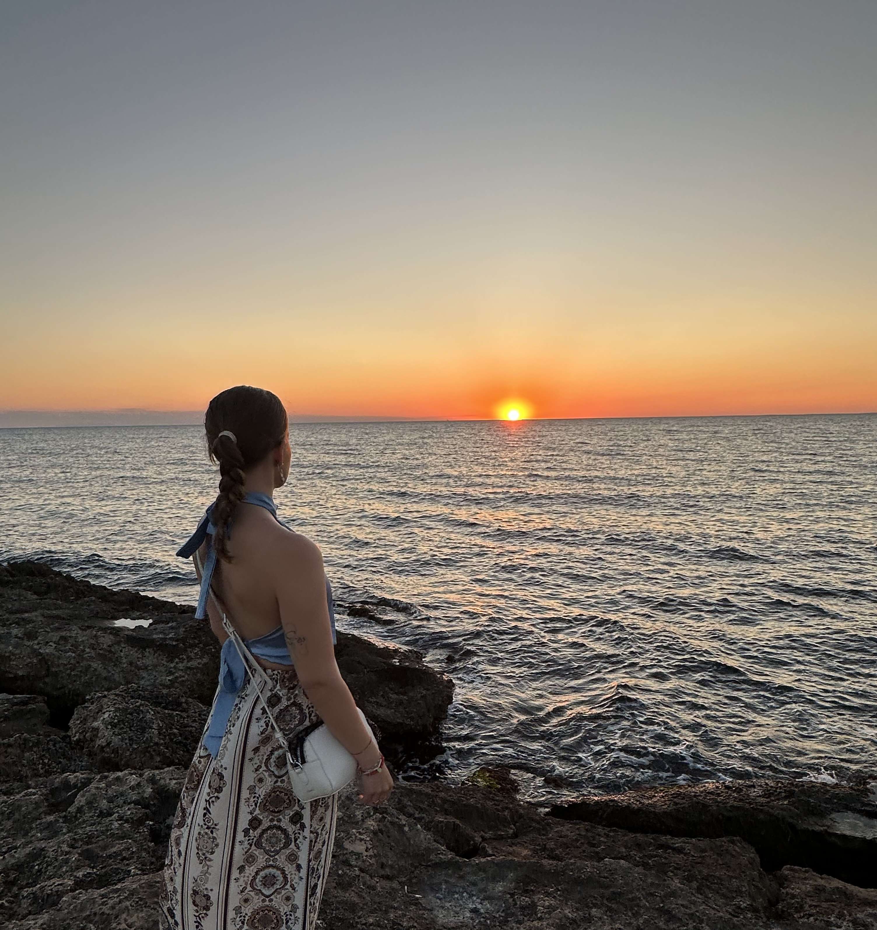 Persona di spalle che osserva tramonto sul mare