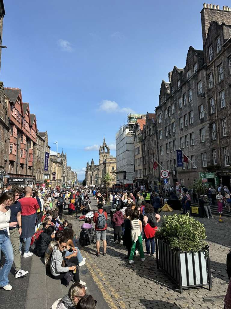 Persone su Royal Mile che assistono ad artisti di strada, la Cattedrale di St Giles sullo sfondo