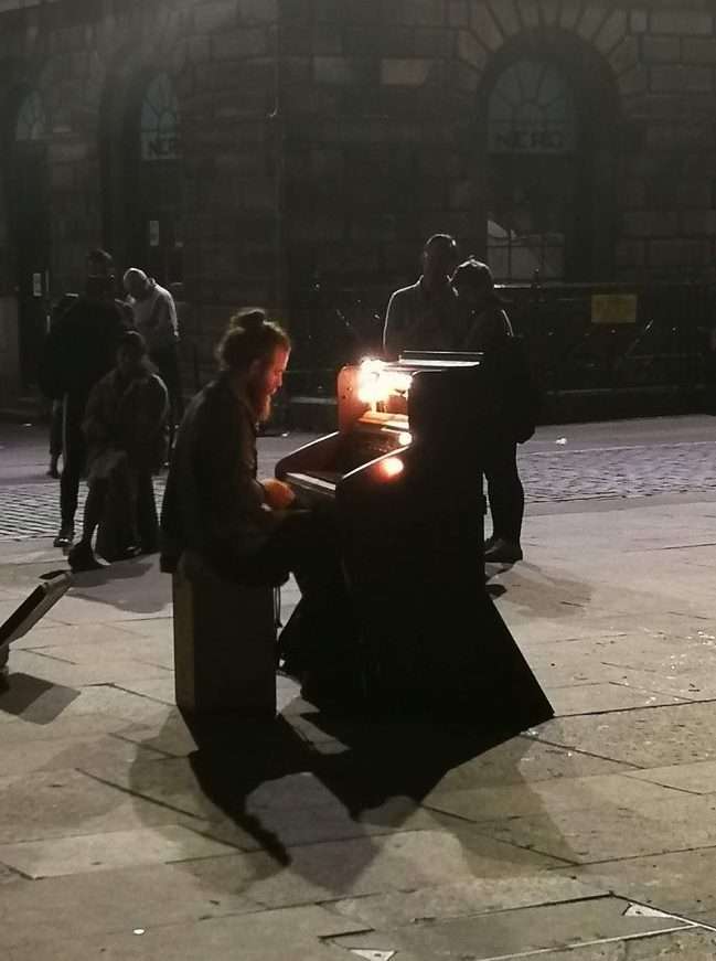 Persona che suona un pianoforte per strada di sera