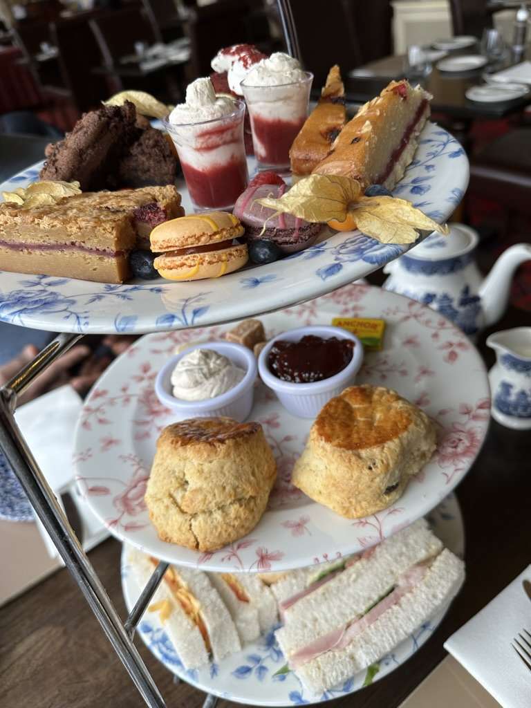 3 piatti in verticale con sandwich, paste dolci e tortine