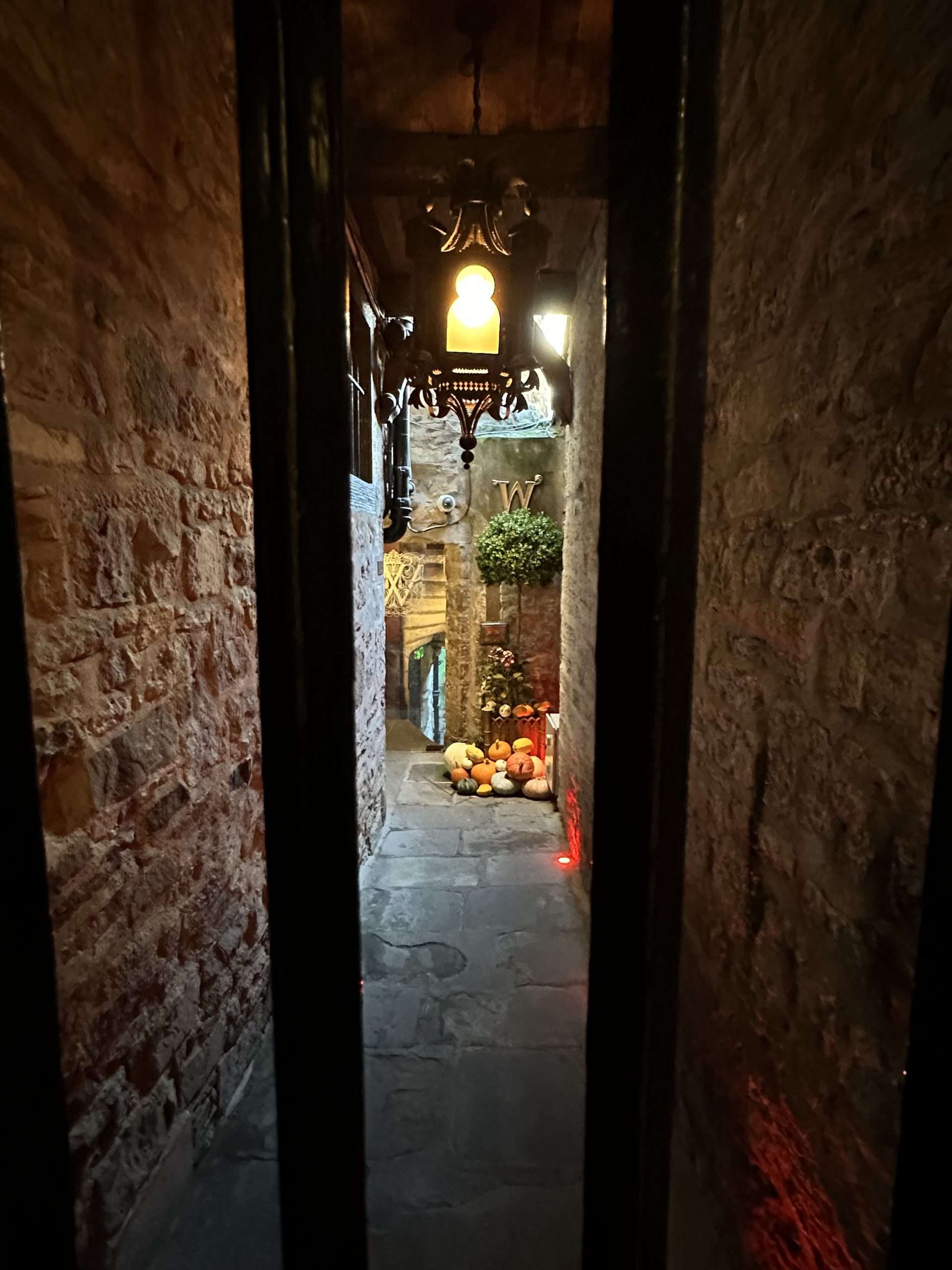 Stretto vicolo con cancello, lampadario e zucche Halloween