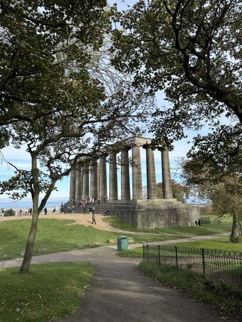 Sentiero asfaltato in mezzo ai prati della collina di Calton Hill e sullo sfondo il monumento Nazionale della Scozia