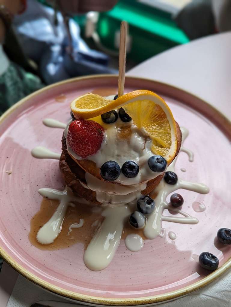 Piatto con pancakes impilati con crema, mirtilli, sciroppo e fragola