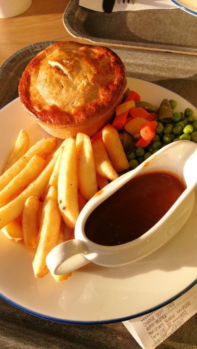 Piatto con patatine fritte, tortino, piselli e tazzina con salsa