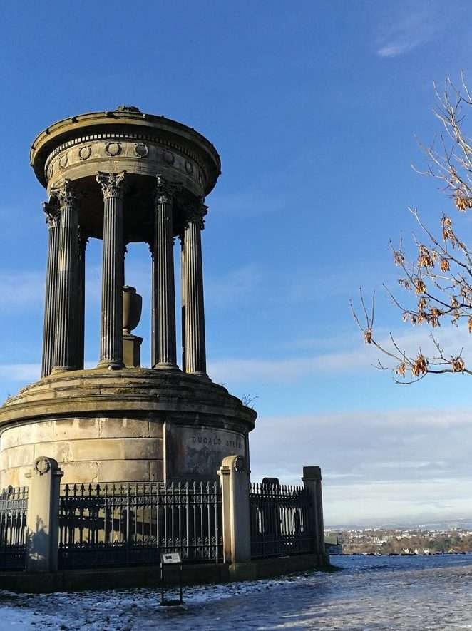 Monumento a Dugald Stewart sulla collina di Calton Hill, pavimento ricopero di neve e vista in fondo a destra della città