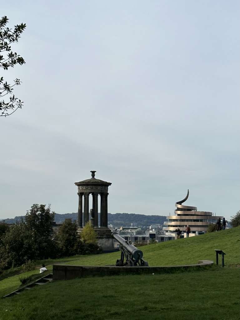 Prato della collina di Calton hill e sullo sfondo monumento Dugald Stewart e l'iconico edificio di St James Quarter
