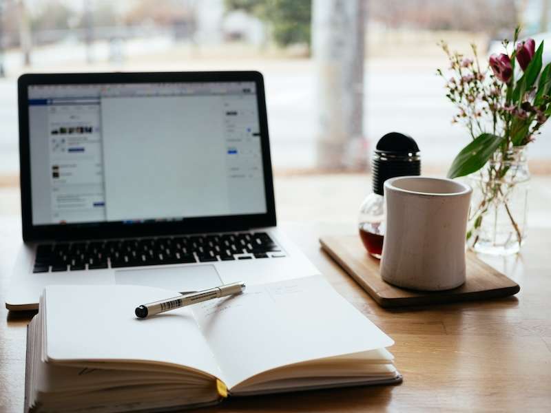 Libro aperto su tavolo legno con tazza ceramica e pc