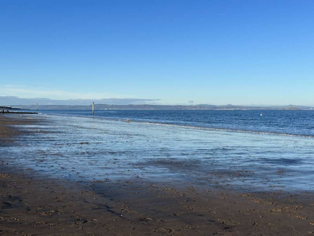 Spiaggia a Portobello di giorno con la bassa marea e pozzanghere d'acqua sulla sabbia dorata