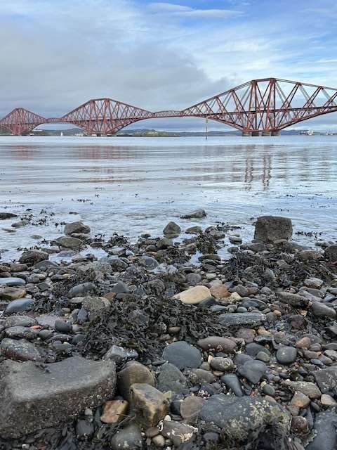 Pietre in riva mare con ponte rosso