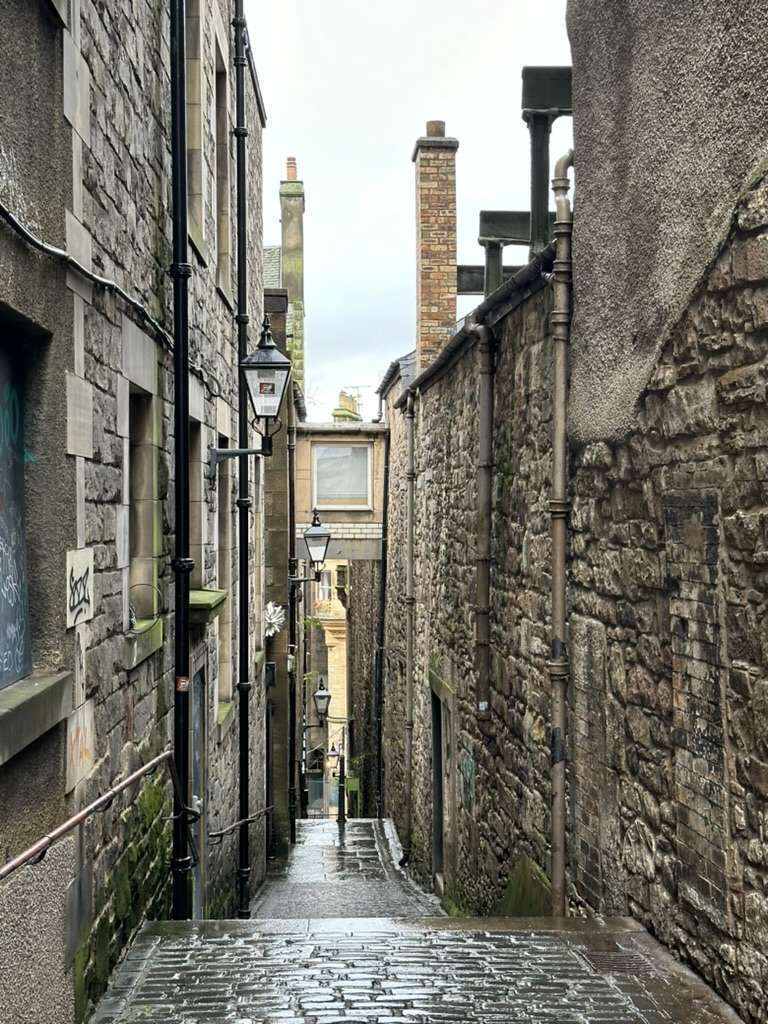 Stretto vicolo tra edifici centro storico con lampioni antichi