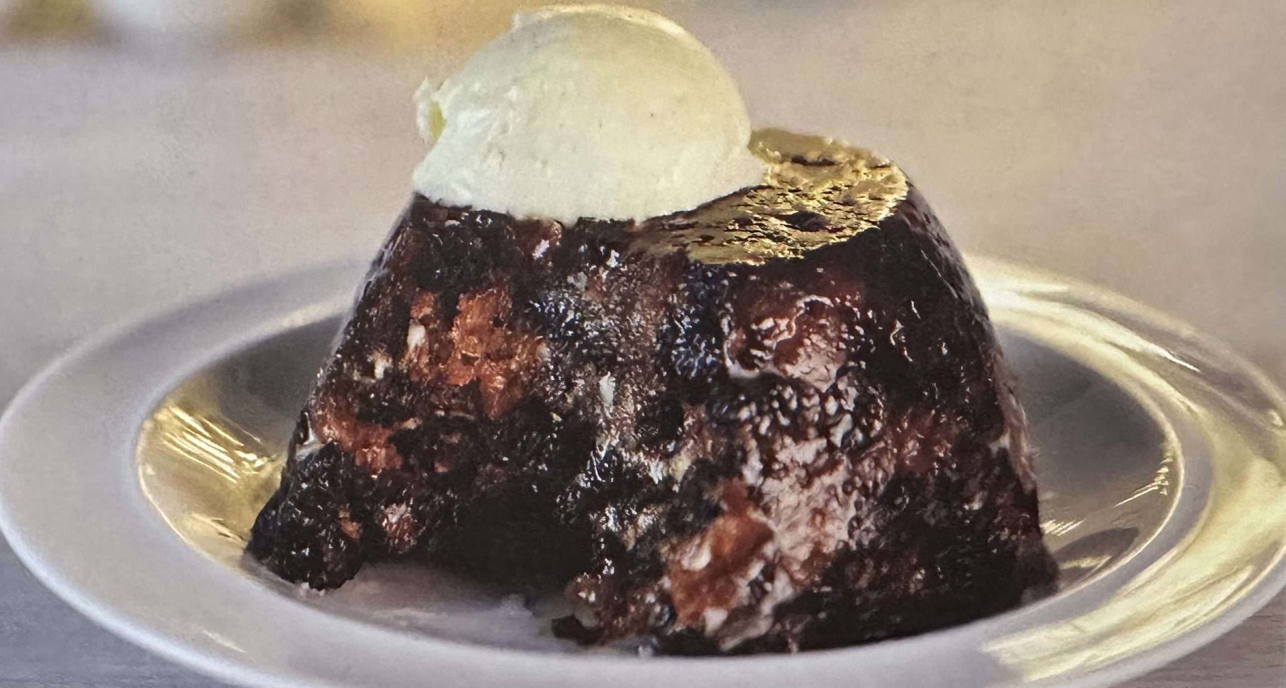 Piatto con dolce Christmas pudding con pallina gelato sopra 