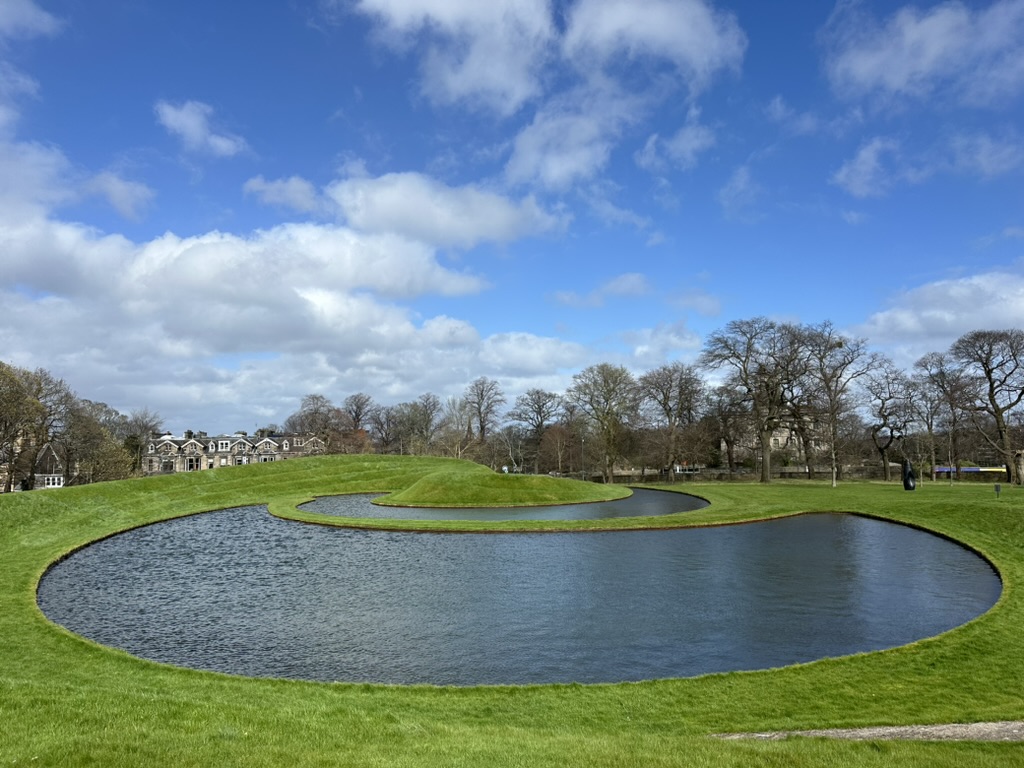 Veduta esterna del Modern One a Edimburgo con il grande giardino geometrico a spirale progettato da Charles Jencks, che include un lago e colline d'erba.