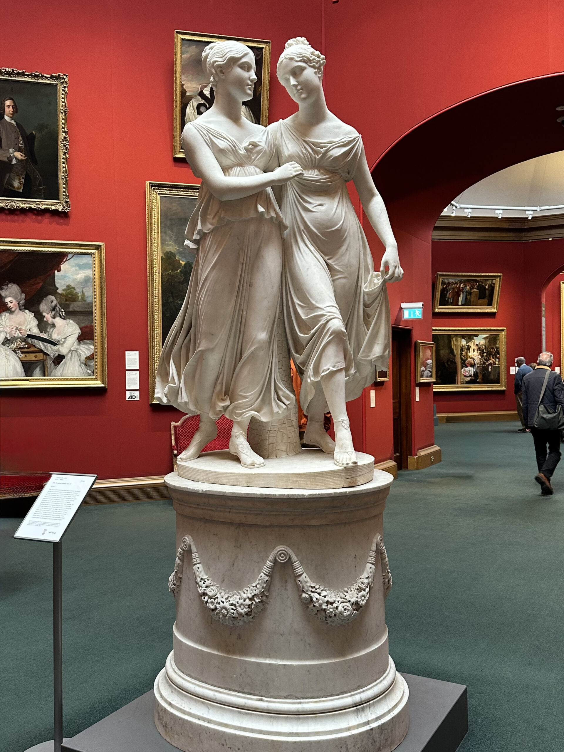 Interno della Scottish National Gallery a Edimburgo con visitatori, quadri alle pareti e una statua in primo piano