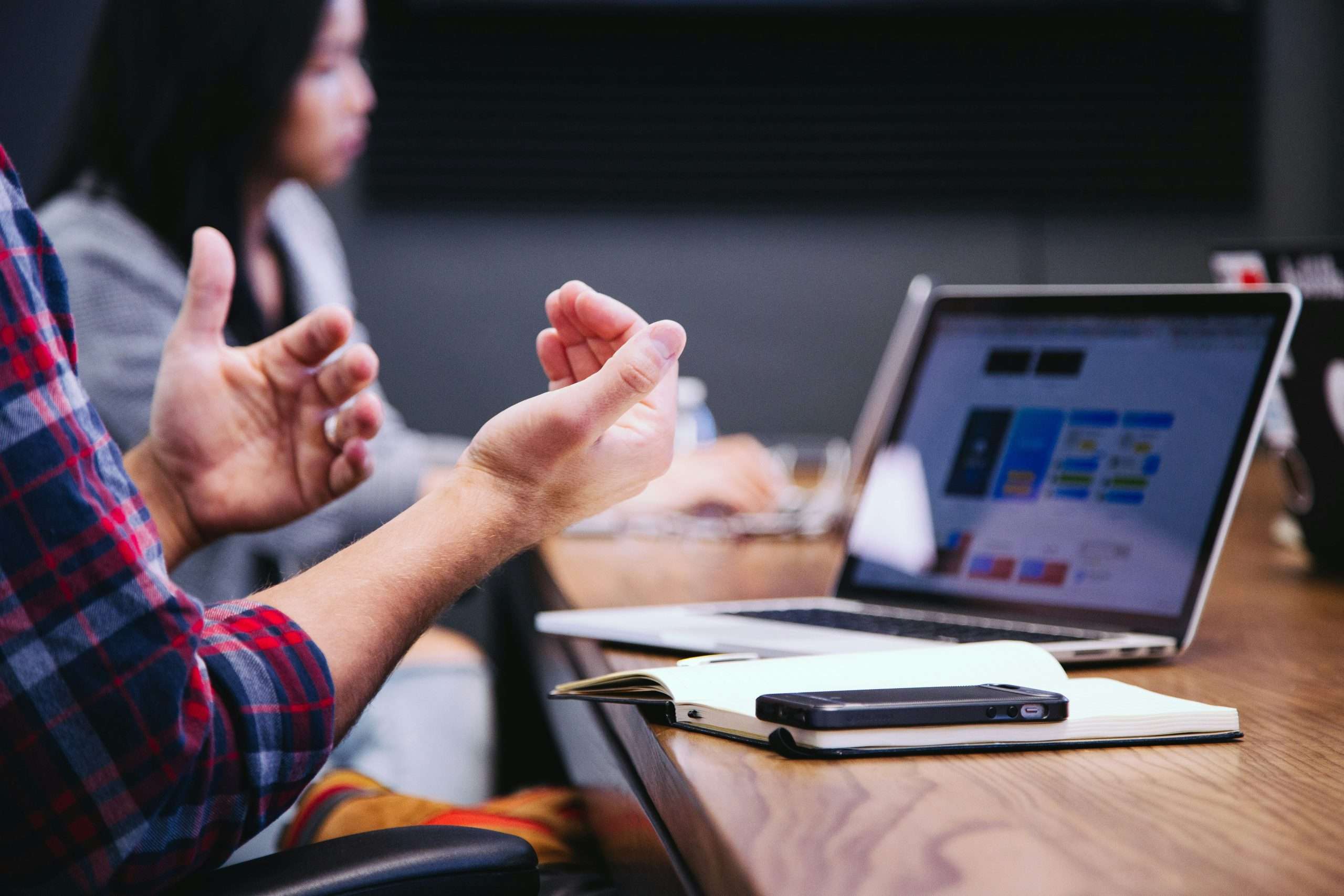 due persone ad una scrivania di legno che guadano un pc per colloquio di lavoro in uk