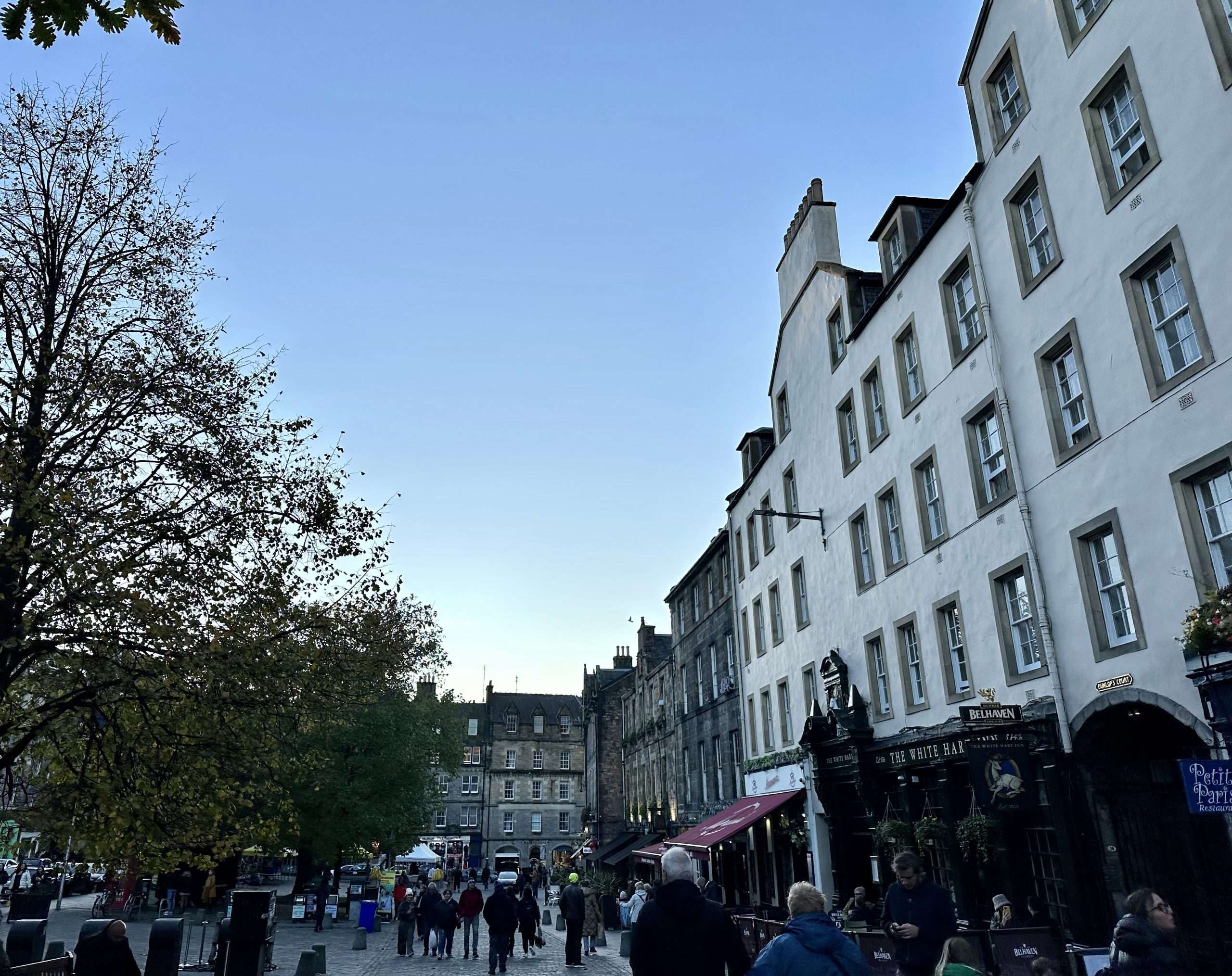 Piazza con edifici sulla destra e gente per strada a Edimburgo