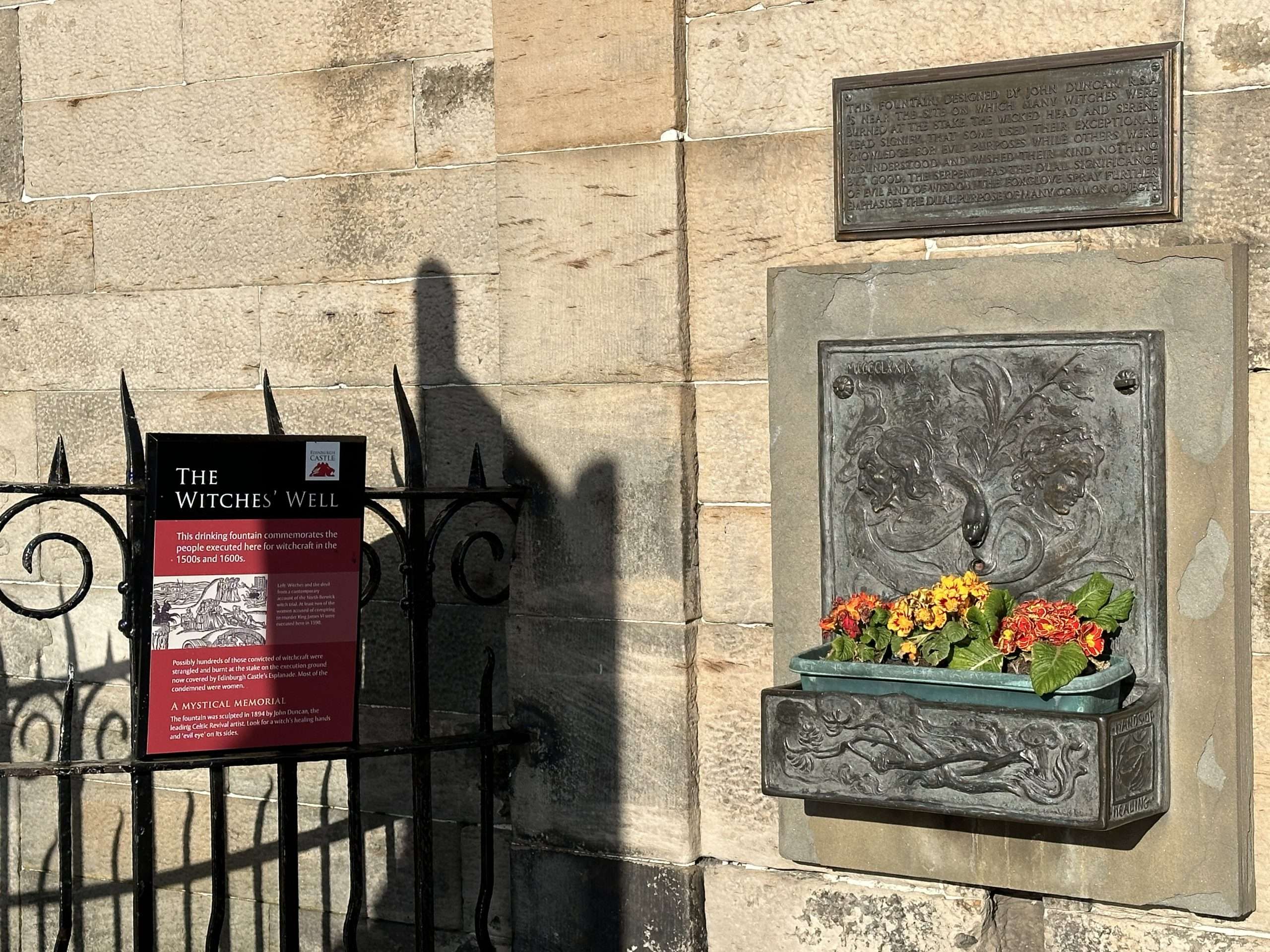 Fontanna alla parete con cartello sul cancello a sinistra, pozzo delle streghe centro storico Edimburgo