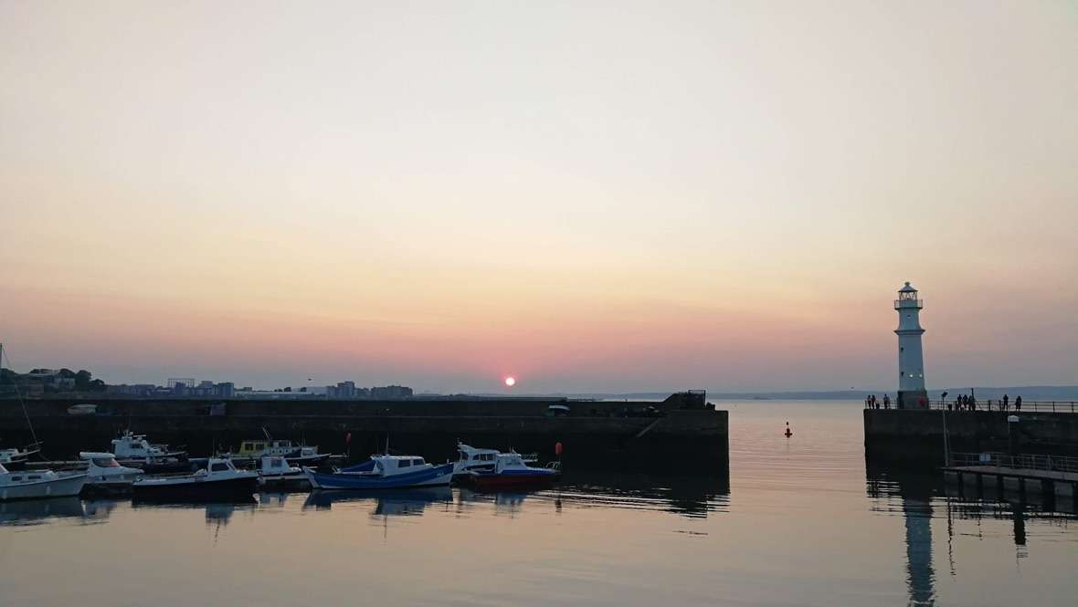 tramonto sul mare con barche nel piccolo porto