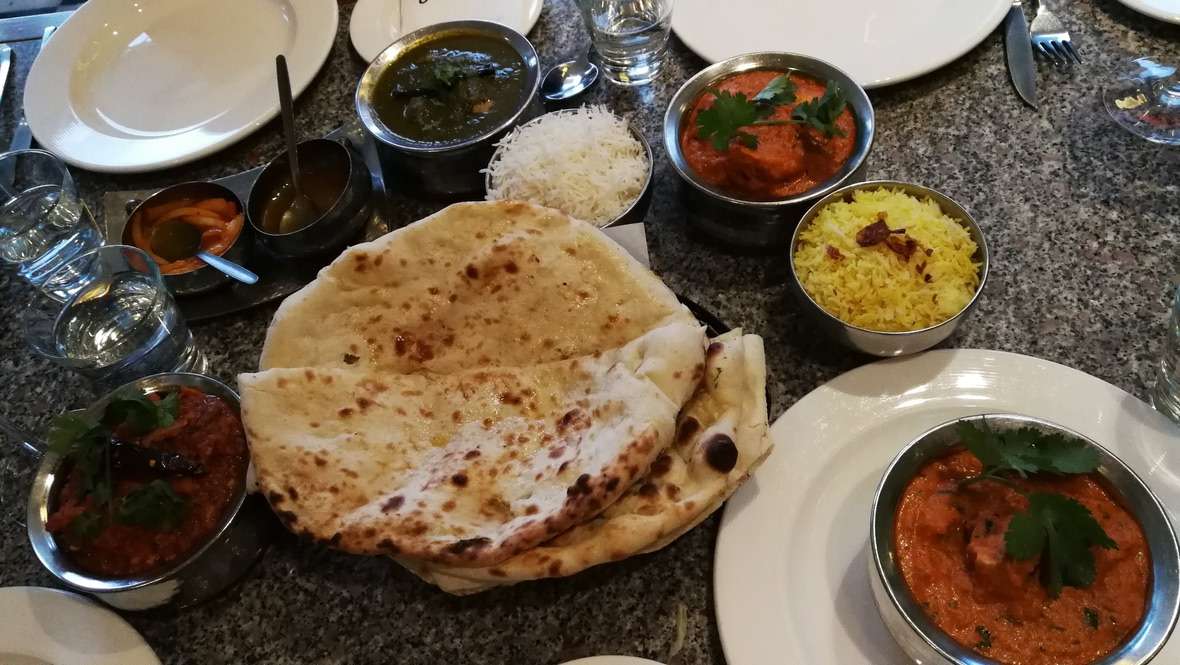 Tavolo con pane, salse e carne tipico di cucina indiana