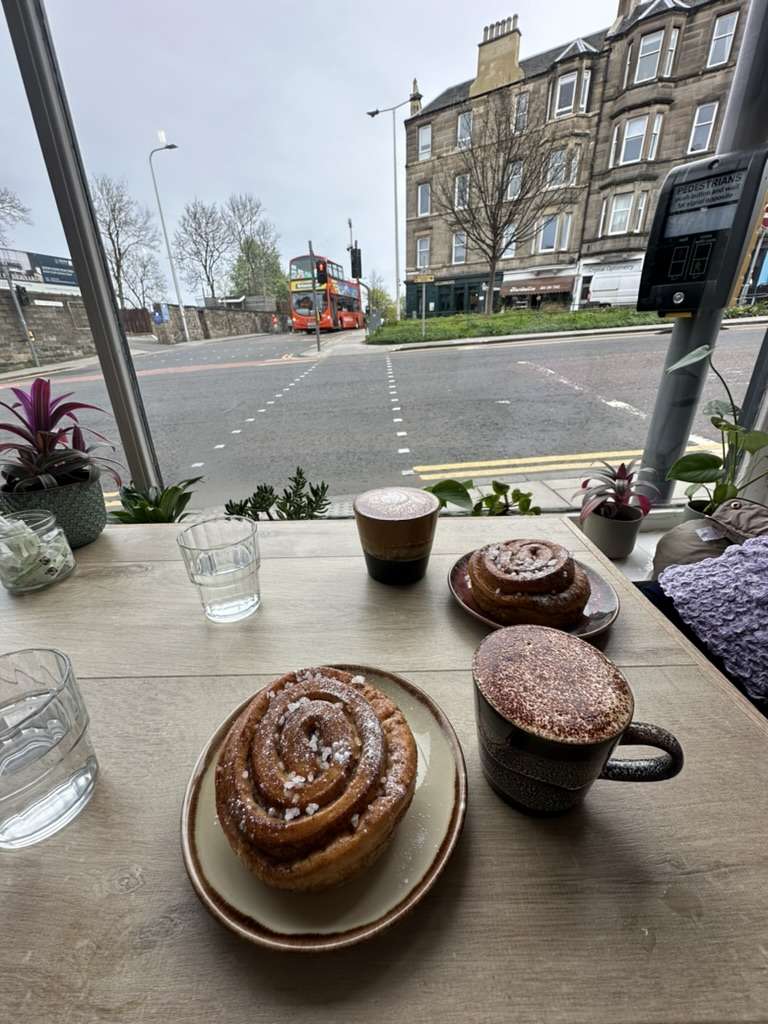 Tavolo di legno con cappuccino e brioche in un cafe di edimburgo