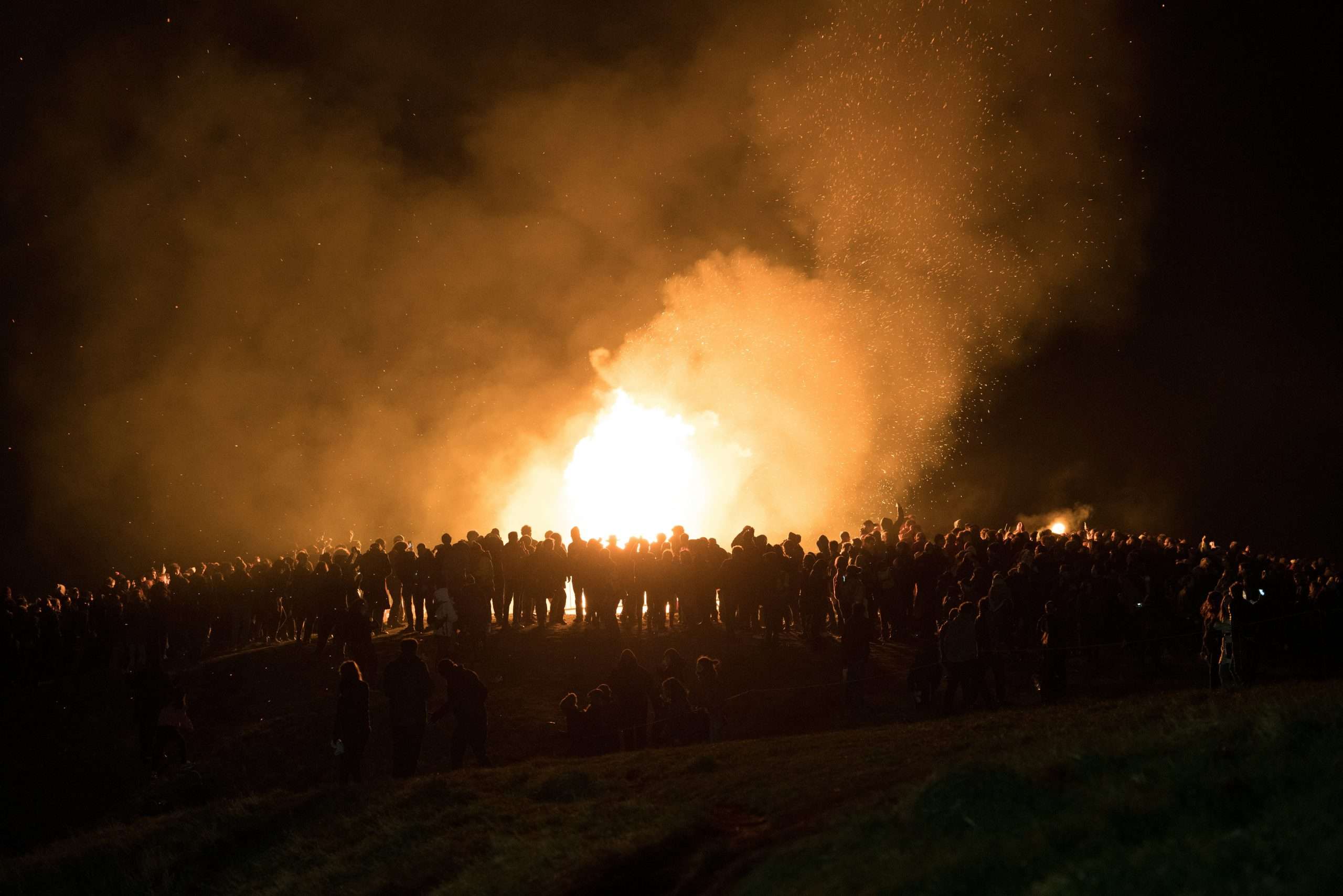 gruppo di gente al buio su un colle con la luce di un falò al Beltane Fire festival di Edimburgo