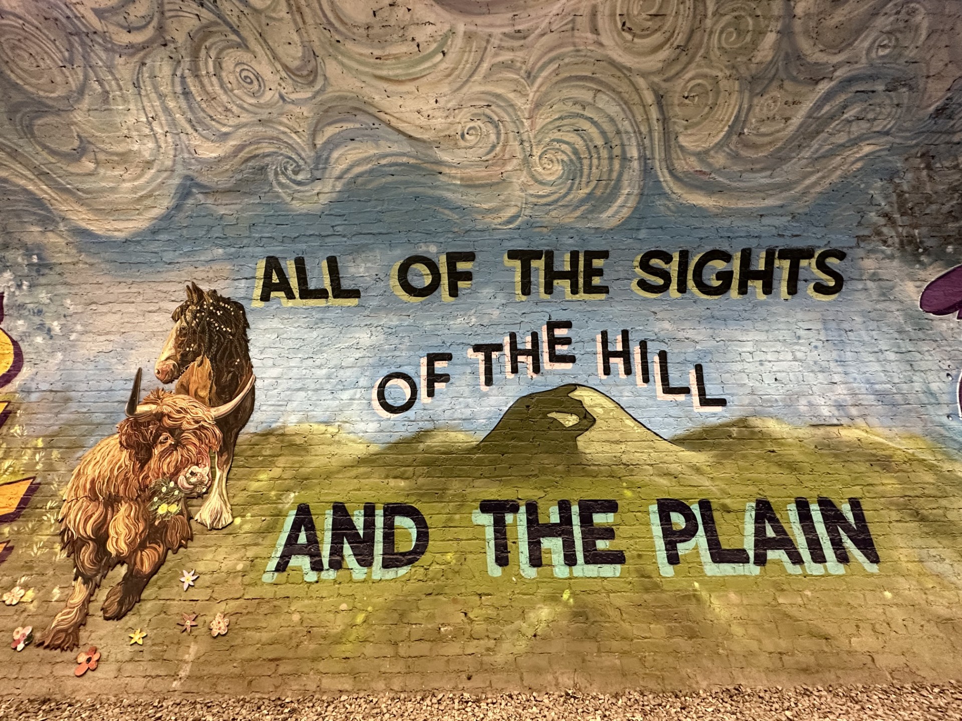 Murale del Colinton Tunnel a Edimburgo con una Highland cow e la scritta "All of the sights of hill and the plain"