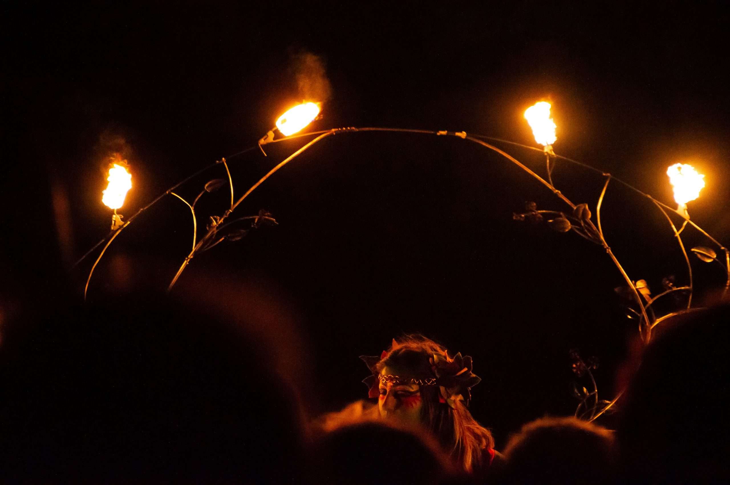 Ragazza con maschera che balla attorno a un cerchio di fuoco per il Beltane fire festival a Edimburgo