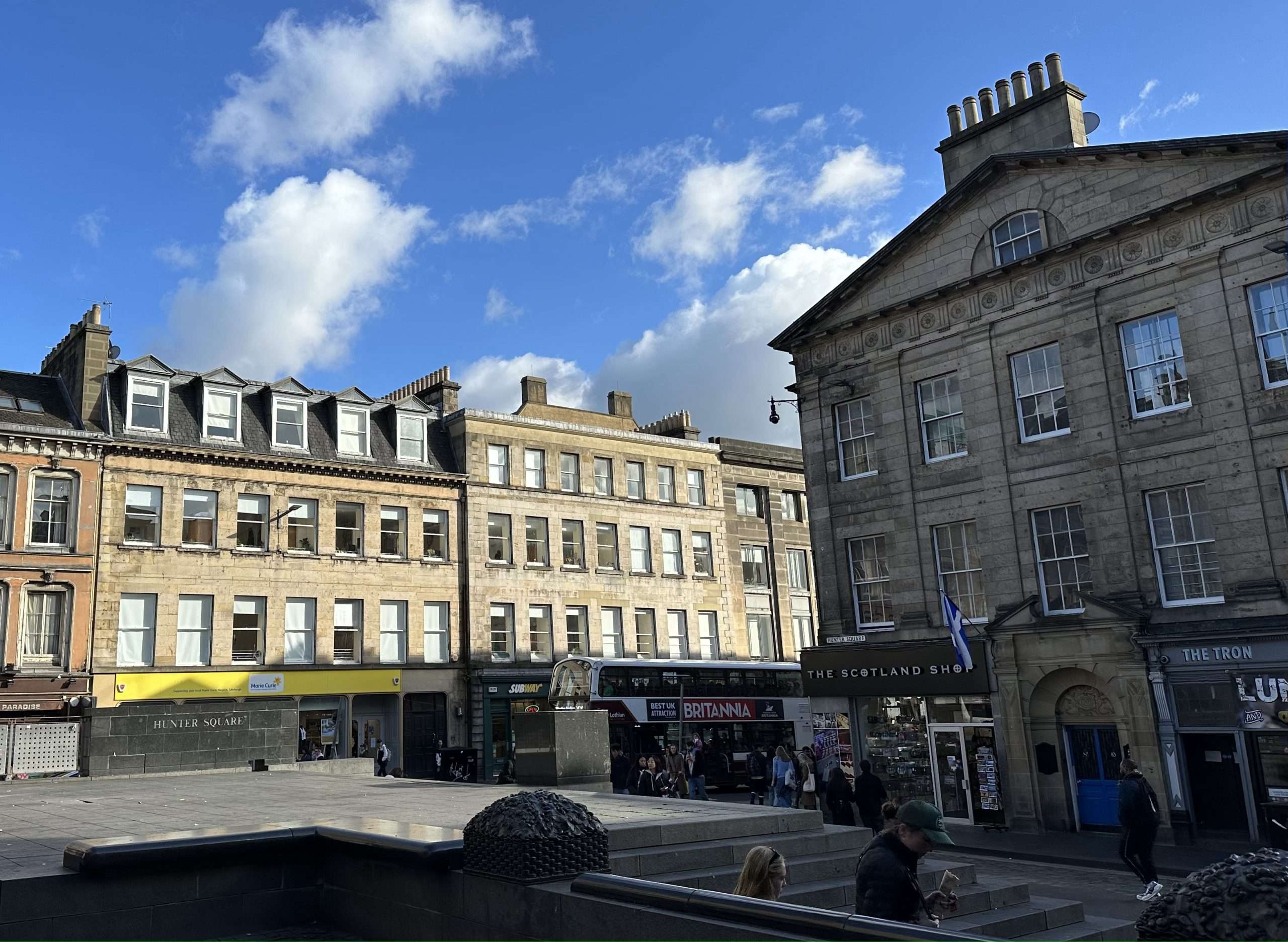 Piazza di Edimburgo con palazzi atorno e un pub in fondo chiamato 'The tron'