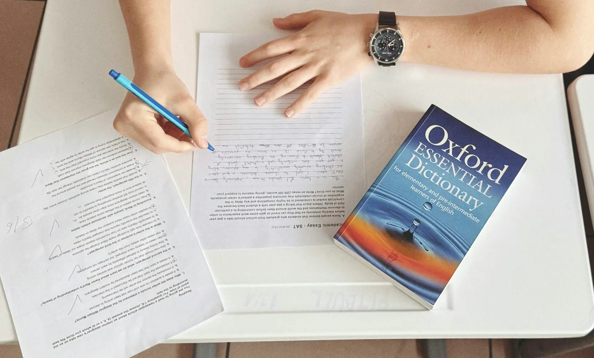 Libro di Oxford su un bagno con fogli e due braccia poggiate, una mano scrive