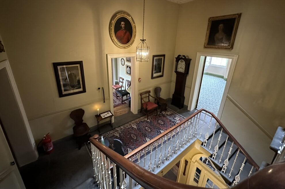 Scorcio dell'antico vano scale interno della Georgian House a Edimburgo, con vista sui dipinti d'epoca, arredi storici e porte che conducono alle sale superiori.