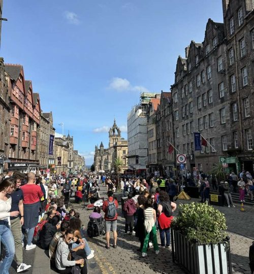 Persone su Royal Mile che assistono ad artisti di strada, la Cattedrale di St Giles sullo sfondo