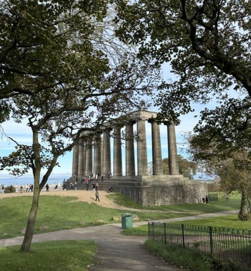 Sentiero asfaltato in mezzo ai prati della collina di Calton Hill e sullo sfondo il monumento Nazionale della Scozia