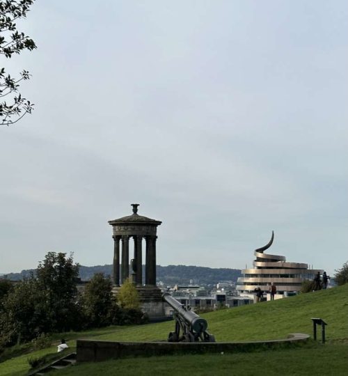 Prato della collina di Calton hill e sullo sfondo monumento Dugald Stewart e l'iconico edificio di St James Quarter